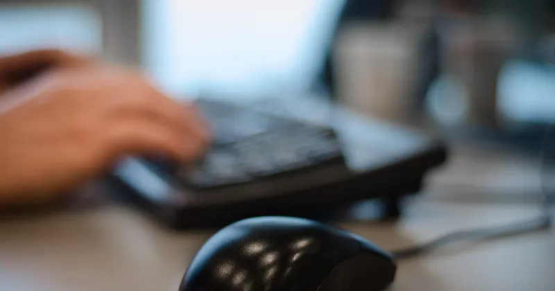 Manos de un empleado trabajando con el teclado y el ratón en un puesto de oficina